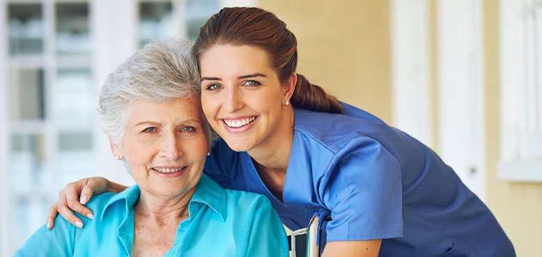 caregiver and elderly woman smiling at the camera