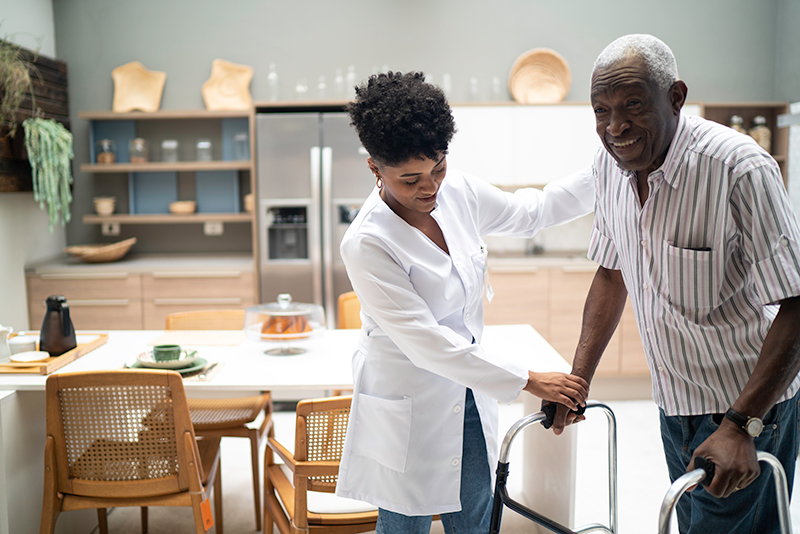 young female caregiver helping senior man use his walker