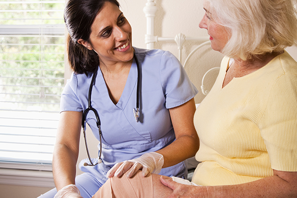 Nurse wrapping woman's knee with bandage