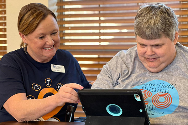 Nexion employee helping older patient use tablet
