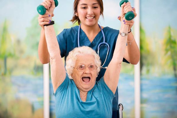 Physical therapist helps strengthen senior woman's arm muscles during physical therapy session