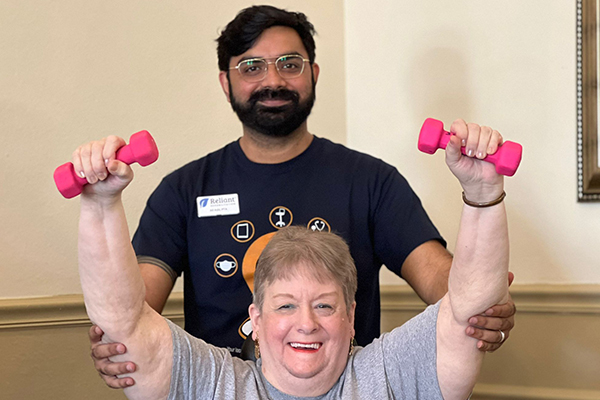 Nexion employee posing with patient holding up weights