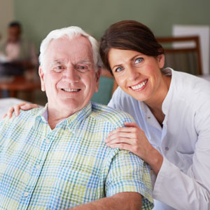 caregiver with her arms around an elderly man