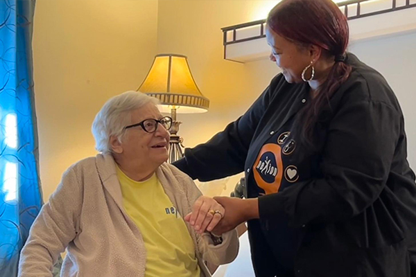 Nexion employee smiling at patient while helping her up