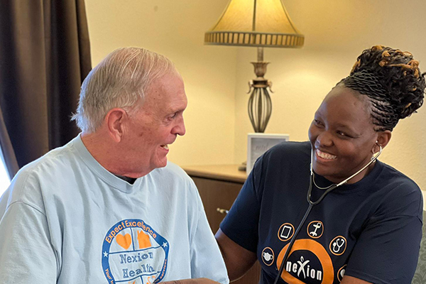 Nexion employee taking vital signs of elderly patient while smiling