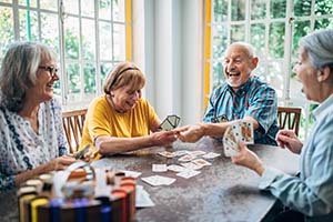 Group of senior friends playing cards in the nursing home and having fun