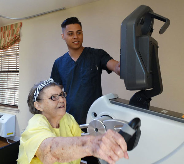 Nexion resident working with employee on hand bike exercises