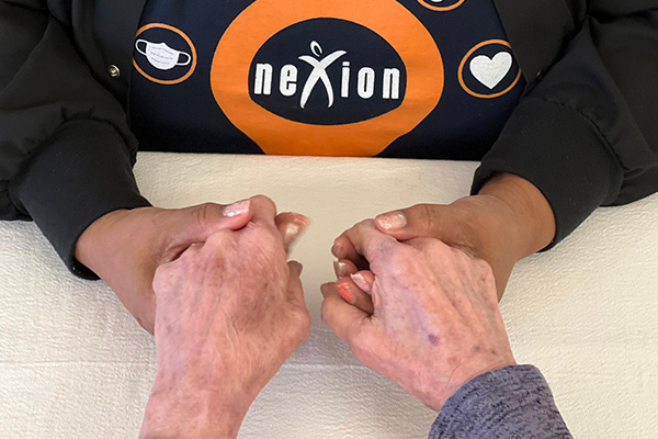 Nexion employees holding elderly patient's hands