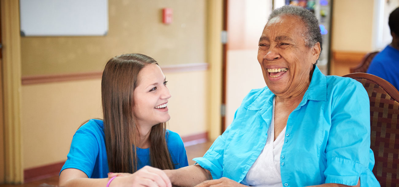 Young staff member laughing with elderly woman