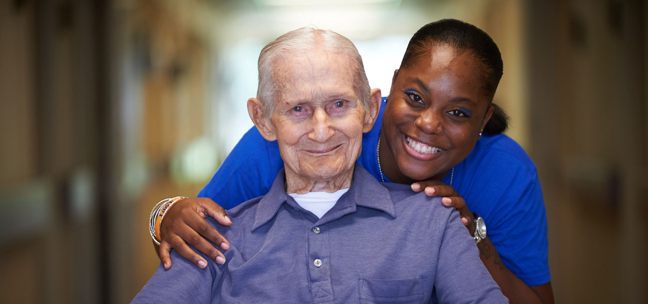 Staff member and elderly man posing for picture