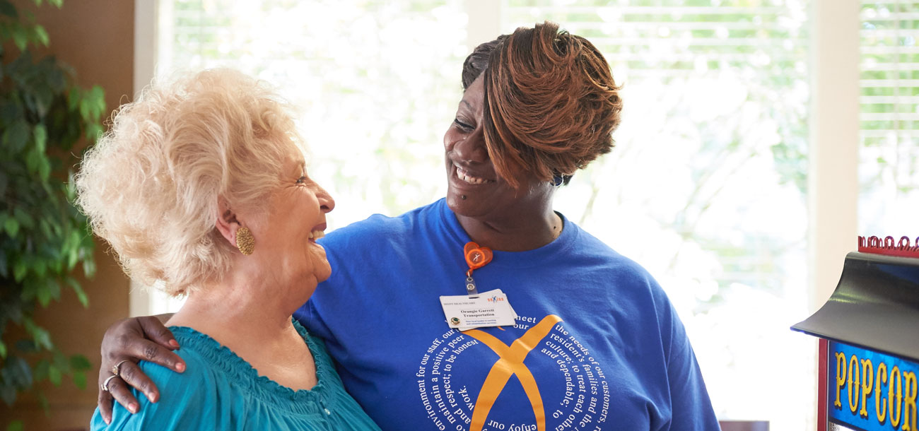 Staff member and elderly woman smiling and talking